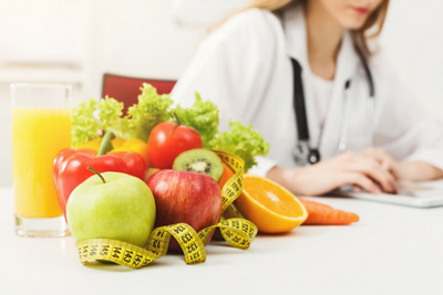 Nutritionist desk with healthy fruit, juice and measuring tape. Dietitian working on diet plan. Weight loss and right nutrition concept