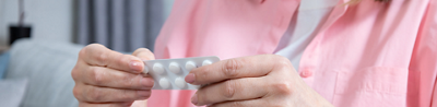 Woman reading medication instructions while holding a blister pack of pills 