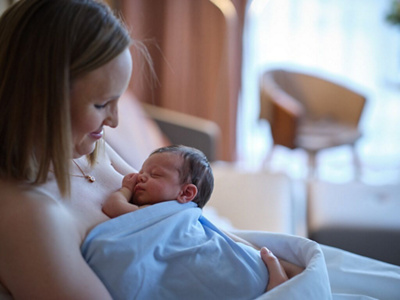 Junge Mutter hält Neugeborenes