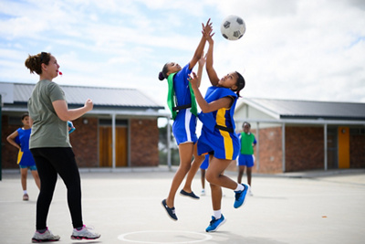 Action shot of a netball player catching a ball on an outdoor sports court 