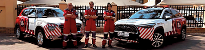 Three paramedics standing next to two ER24 rapid response vehicles 