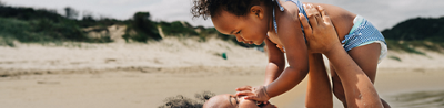 Mother lifting her baby playfully on the beach