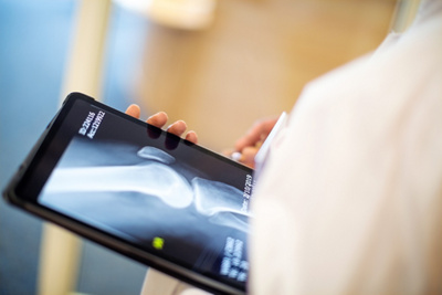Close-up of a digital tablet in hand of a female doctor. Medical professional looking at x-ray image of a patient.