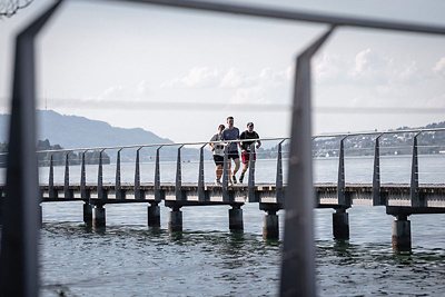 3 Läufer des Walk the Lake auf Steg am Zürichsee