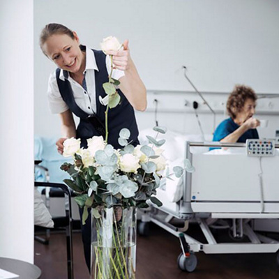 Hotel services employee takes care of the flowers in patient rooms.