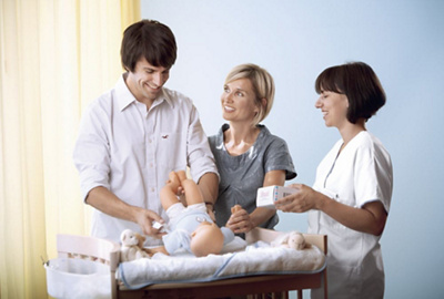 Eltern üben Windeln wechseln an einer Puppe