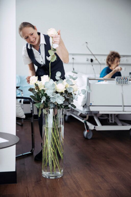 Hotelservice pflegt Blumen im Patientenzimmer