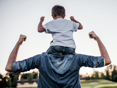 Mann trägt Kind auf den Schultern