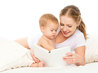 Mother reading  book baby in bed before going to sleep