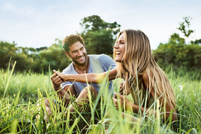 Shot of loving young couple having fun outdoors in grass field. Man and woman enjoying a day in meadow.