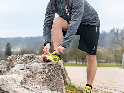 Jogger schnürt sich die Schuhe und beugt dabei sein Knie.