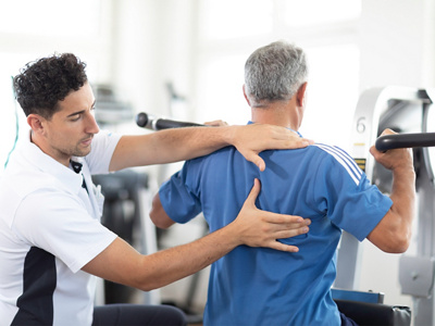 Physiotherapeut zeigt Patient eine Schulterübung