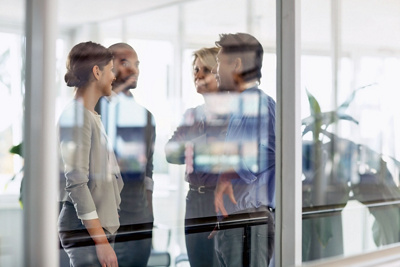View of businesspeople conversing through glass wall in office
