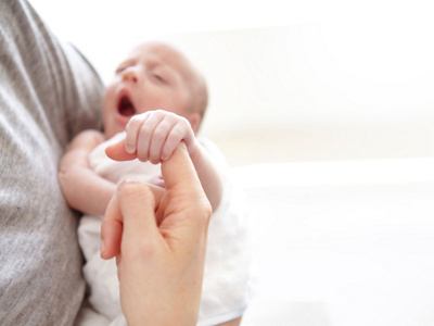 Baby hält den Finger von der Mutter