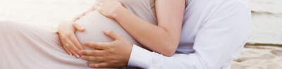 Paar, das die Hände auf den Bauch der schwangeren Frau gelegt hat.