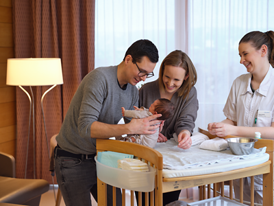 hirslandenbaby-vater-hebt-baby-aus-krippe