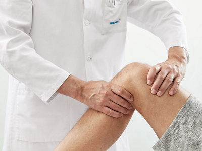 Arzt untersucht Patient am Knie