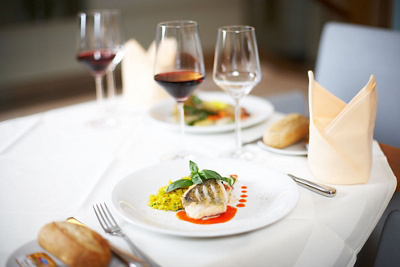 Fischgericht auf weissgedeckten Tisch mit Weingläsern