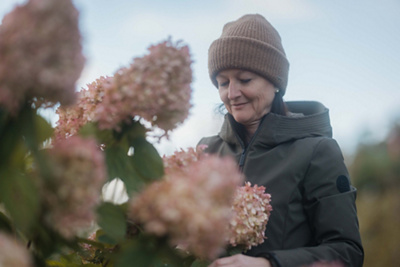 Cristina ist in ihrem Garten und schaut ihre Blumen an.
