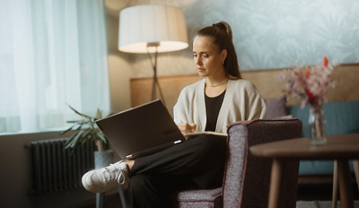 Eine junge Frau arbeitet an ihrem Laptop in einem Café.