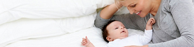 Wöchnerin mit Säugling auf Bett