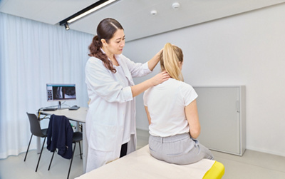 Ärztin untersucht Patientin am Rücken