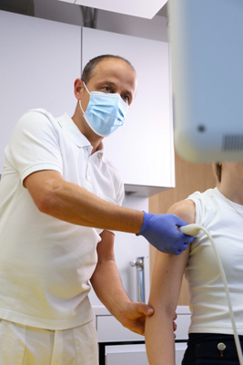 Arzt untersucht Patientin mittels Ultraschall an der Schulter