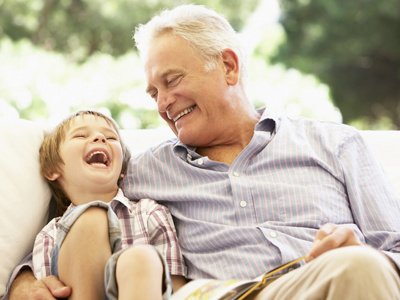Grandfather With Grandson Reading Together On Sofa
